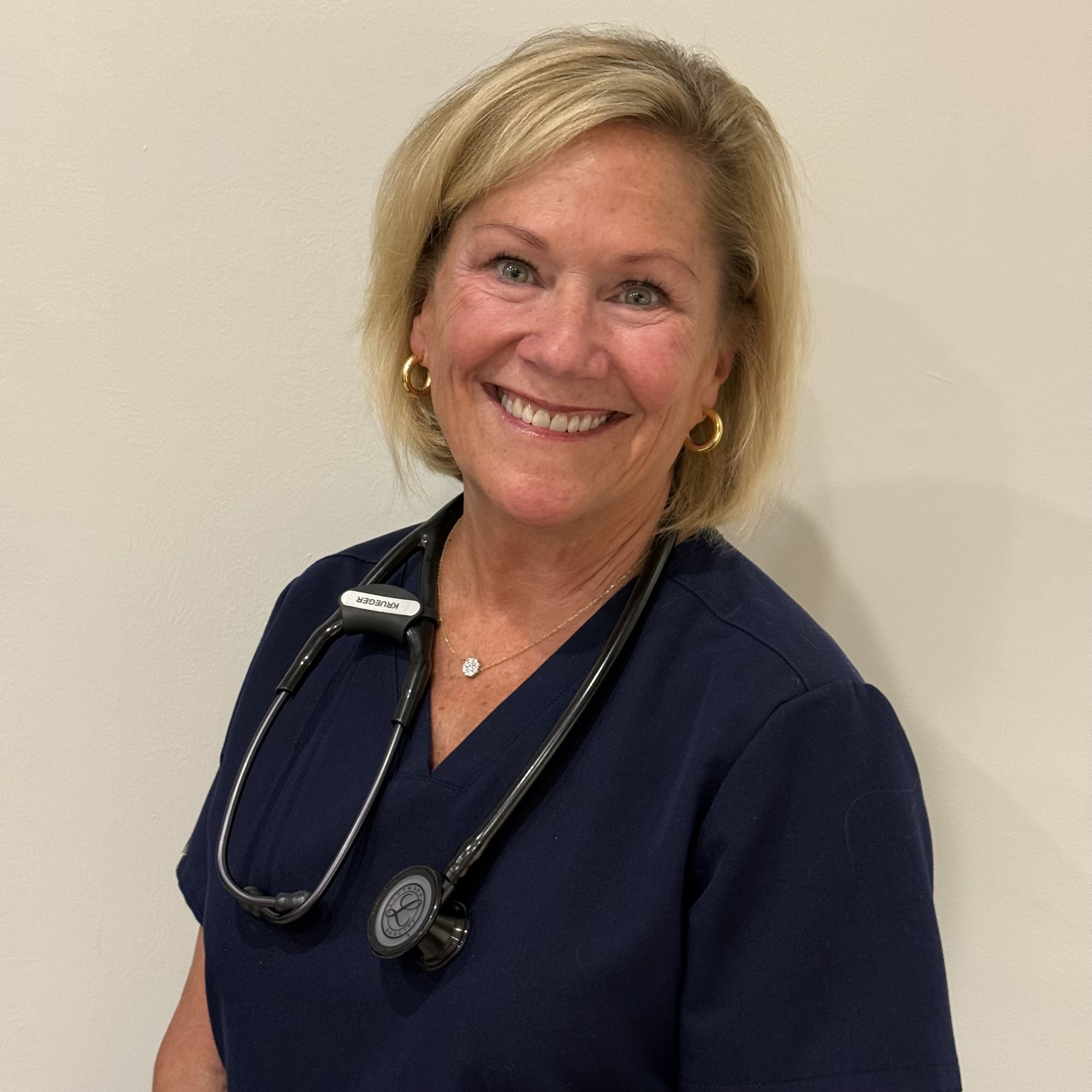 Diane smiling in navy scrubs with stethoscope